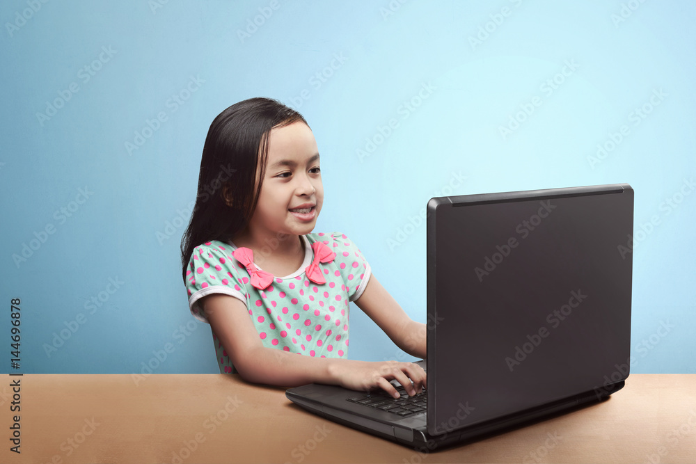 Smiling asian child with laptop computer on the table Smiling asian child with laptop computer on the table