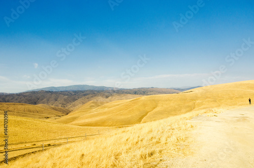an image of broad grass fields, hills and moutains
