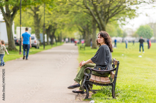 Young woman sitting on bench in summer park © Jevanto Productions