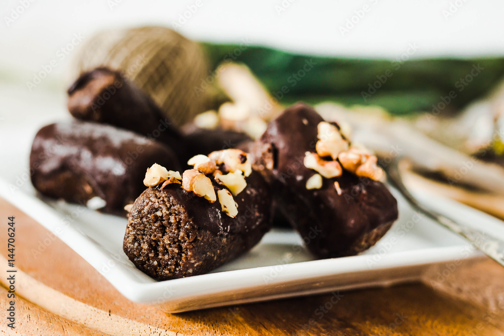 healthy raw chocolate candies with walnuts on a white square plate healthy raw chocolate candies with walnuts on a white square plate