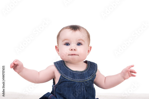 portrait of cute baby girl with big blue eyes and long eyelashes, isolated on white. baby raises his arms up, smiling and looking into the camera