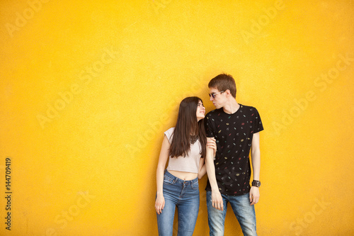Cool couple posing in fashion style on yellow wall. Lifestyle and relationship