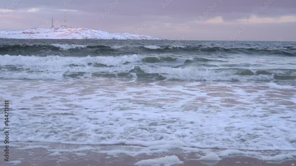 Storm big waves winter north polar arctic rock mountain coast. Dramatic cinematic clouds at horizon. Deep blue color. Snow blizzard wind. reflection of the sky