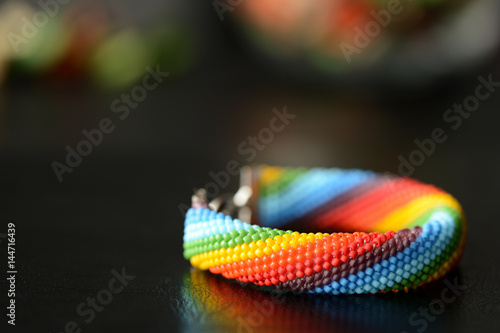 Bead crocheted bracelet of a rainbow colors on a dark background