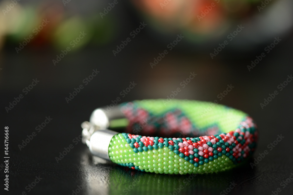 Green beaded bracelet with floral print on a dark background Green beaded bracelet with floral print on a dark background