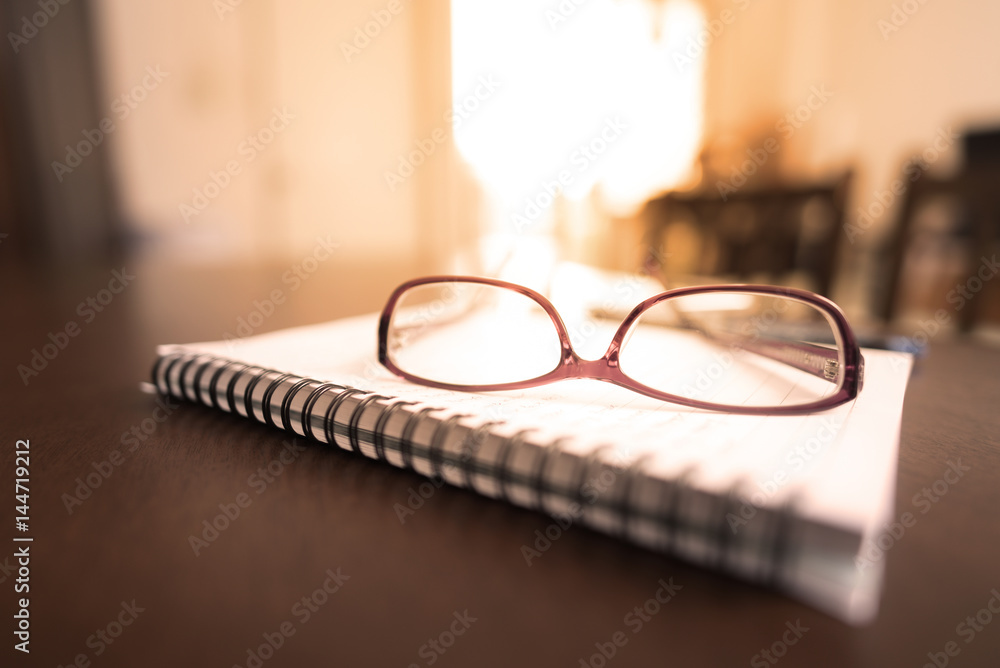 Glasses notebook and pen on brown wooden desk in home office Glasses notebook and pen on brown wooden desk in home office