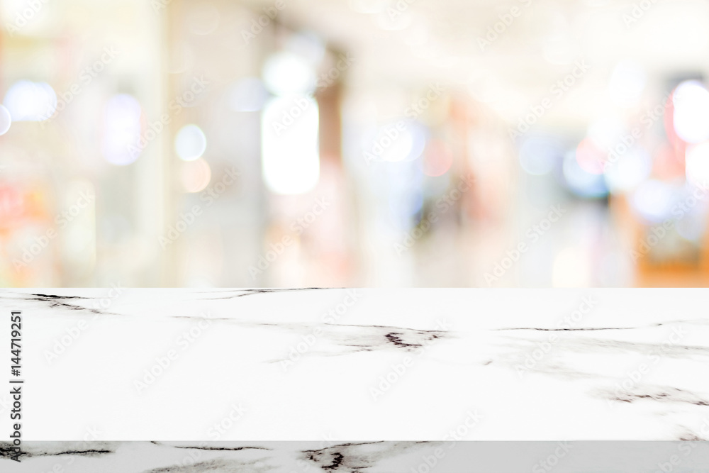 Empty white marble table over blur store background, product and food display montage Empty white marble table over blur store background, product and food display montage