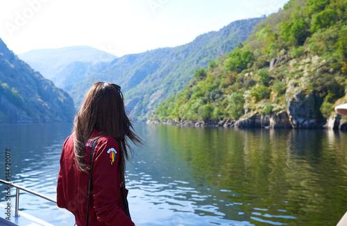 mujer joven de espaldas viajando en barco por los cañones del sil