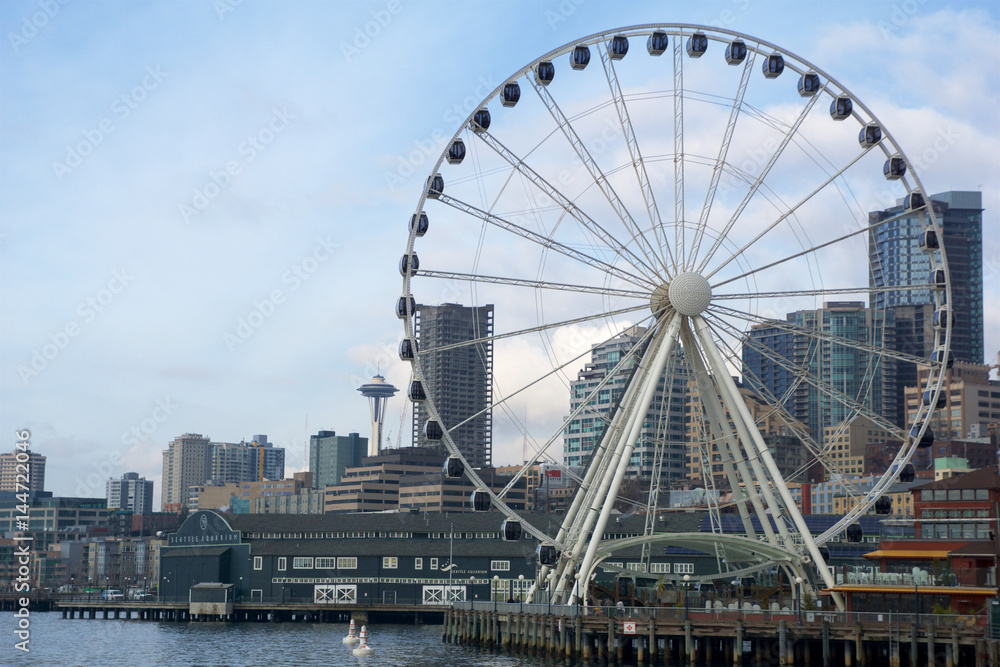 SEATTLE, WASHINGTON, USA - JAN 25th, 2017: A view on Seattle downtown from the waters of Puget Sound. Piers, skyscrapers, Space Needle and Ferris wheel in Seattle city before sunset