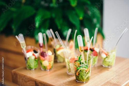 Mini fresh salads with sauce. Catering - served table with appetizers. Selective focus