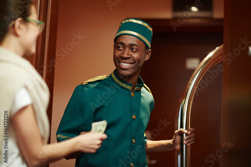 Fotografi Young guest of hotel giving porter money for his help