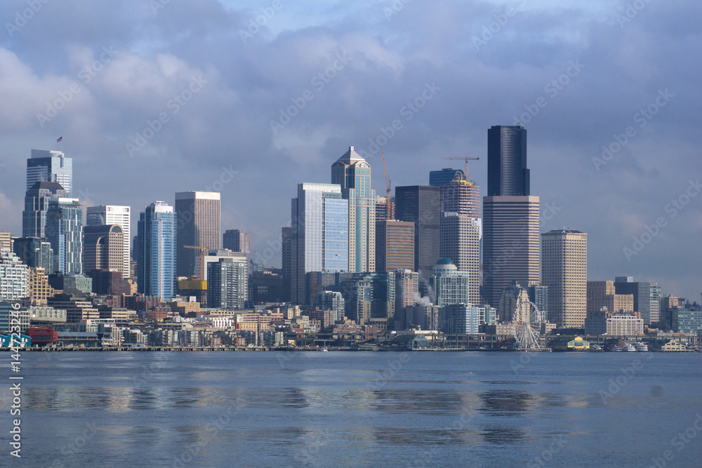 SEATTLE, WASHINGTON, USA - JAN 25th, 2017: A view on Seattle downtown from the waters of Puget Sound. Piers, skyscrapers and Ferris wheel in Seattle city before sunset SEATTLE, WASHINGTON, USA - JAN 25th, 2017: A view on Seattle downtown from the waters of Puget Sound. Piers, skyscrapers and Ferris wheel in Seattle city before sunset