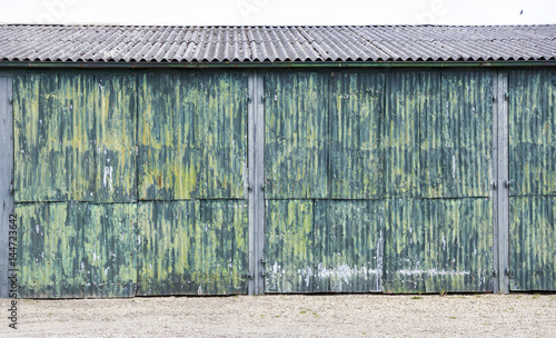 rusty corrugated iron doors of shed with green yellow paint