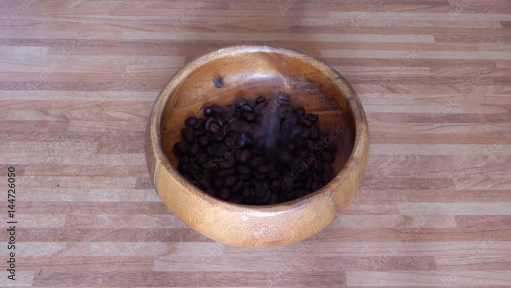 Roasted coffe beans falling in wooden bowl on brown table. Food or cooking theme. With orginal sound of grains drop. Roasted coffe beans falling in wooden bowl on brown table. Food or cooking theme. With orginal sound of grains drop.