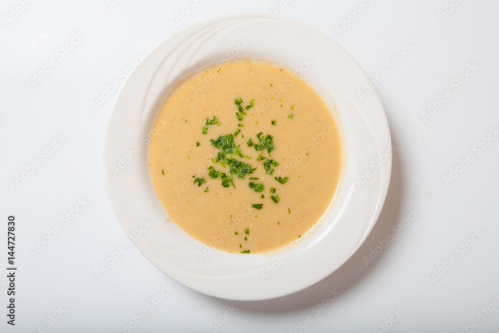 Creamy vegetables soup with fresh herbs in a white bowl Creamy vegetables soup with fresh herbs in a white bowl