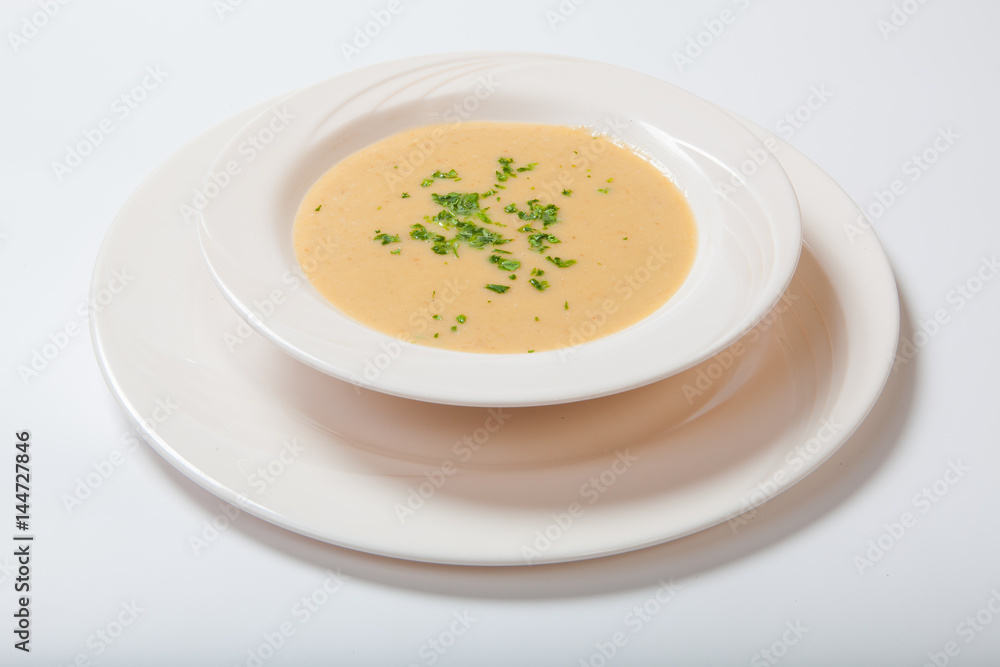 Creamy vegetables soup with fresh herbs in a white bowl Creamy vegetables soup with fresh herbs in a white bowl