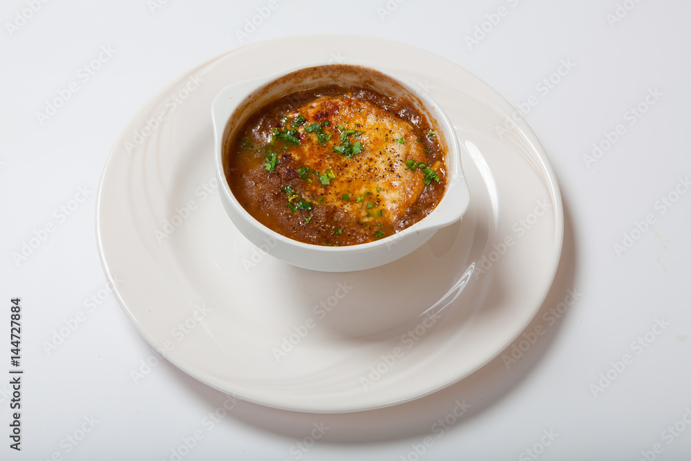 French onion soup in a deep white bowl. French onion soup in a deep white bowl.