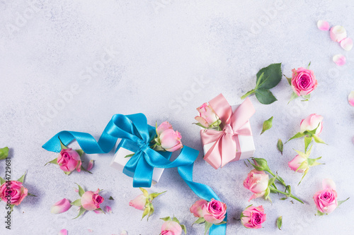 Gift box with blue satin bow and rose flowers on gay
