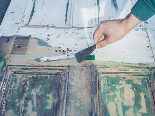 Plakat Hand scraping paint off door