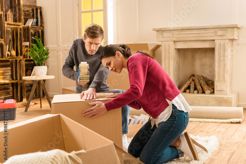 side view of young couple packing things for moving home
