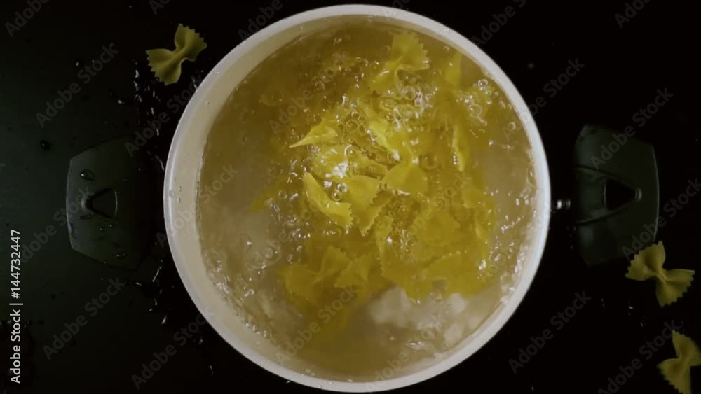 Farfalle paste falls into the pan with water down the top view. Slow motion Farfalle paste falls into the pan with water down the top view. Slow motion