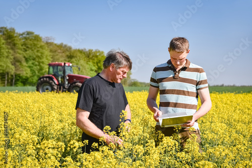 Ackerbau - Ertrag  Landwirt ber  t sich mit seinem Sohn im Rapsfeld