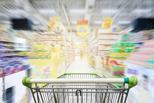 Supermarket aisle with empty green shopping cart