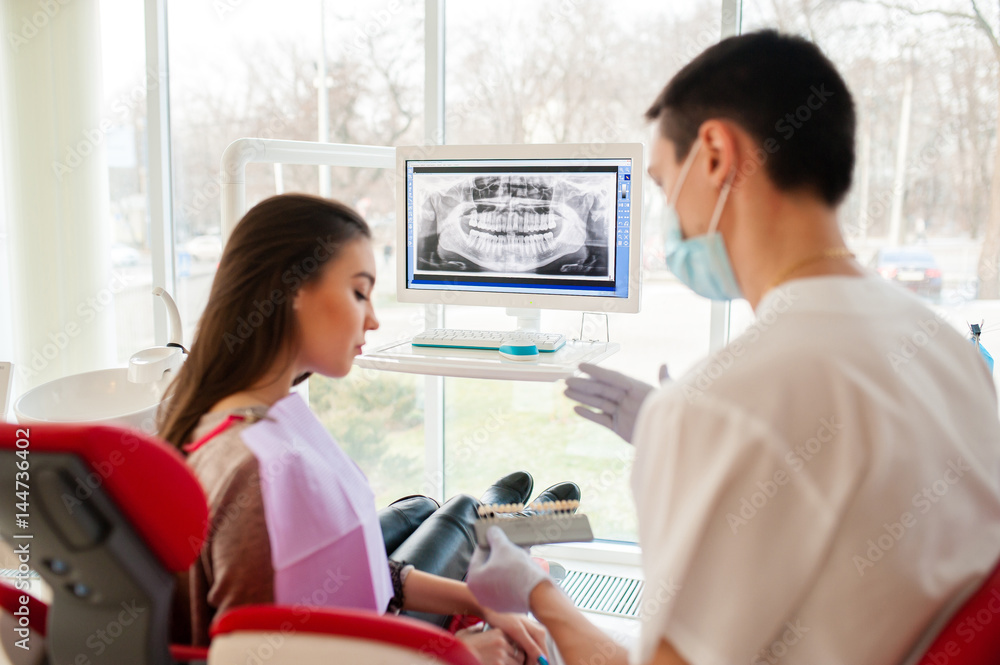 The dentist selects the color of dental implants for a beautiful girl. The dentist selects the color of dental implants for a beautiful girl.