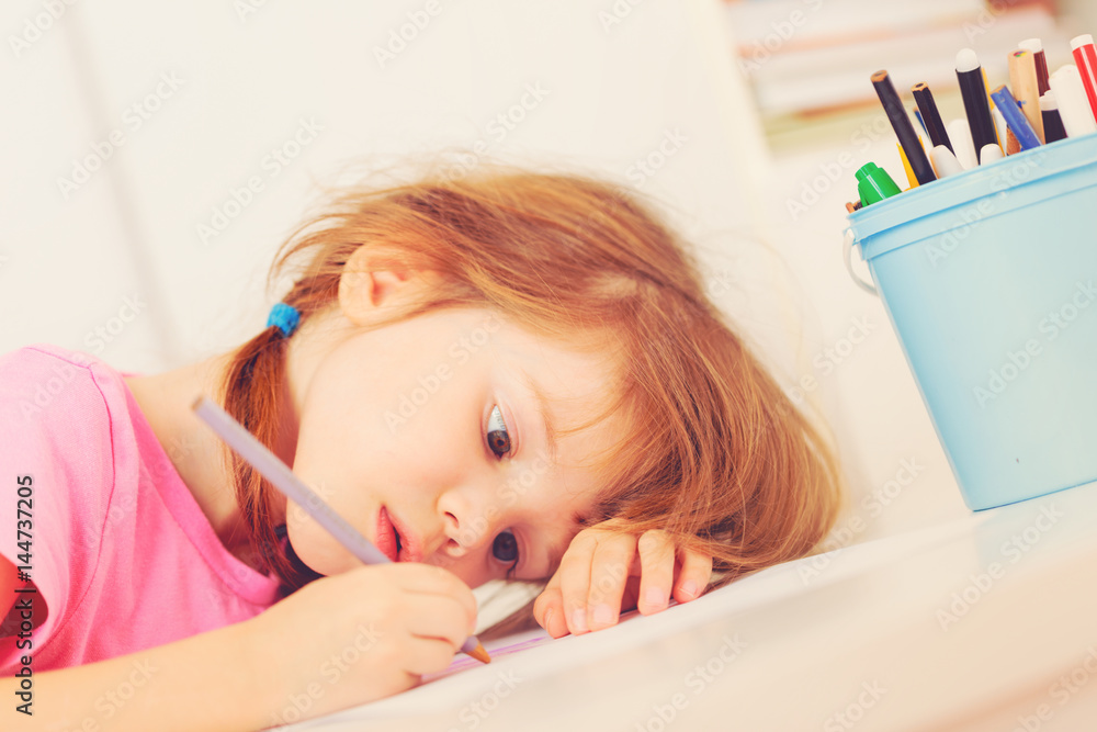 Bored girl drawing lying on the table Bored girl drawing lying on the table