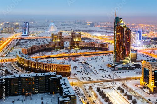 Evening view from the top on a round square with the Administrative and technological complex Transport Tower and the office of KazMunaiGaz. In the distance there is a shopping center Khan Shatyr