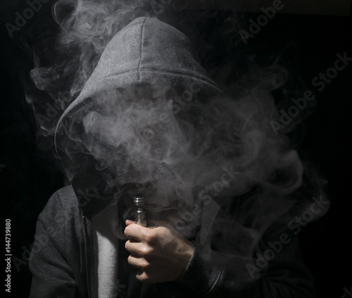 Young person vaping an e cig with lots of clouds. photo