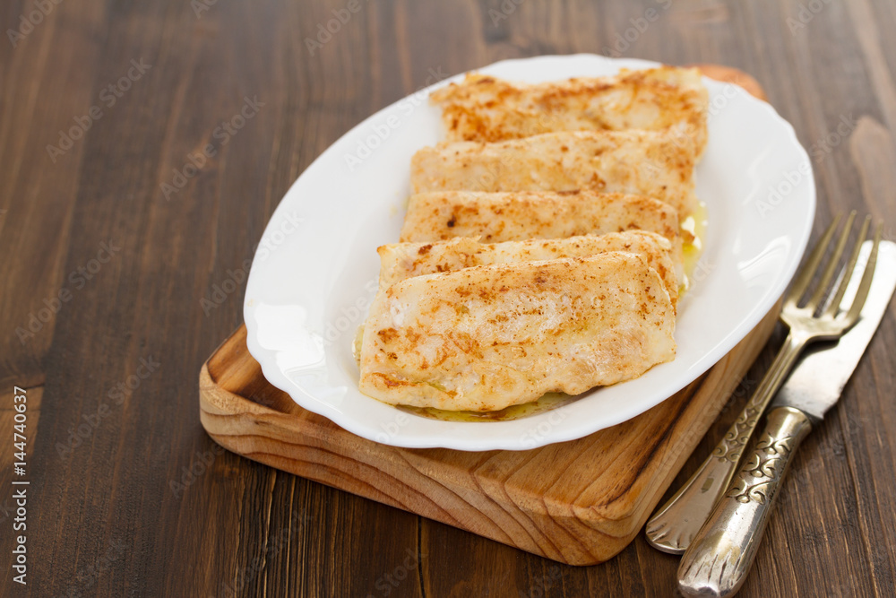 fried fish on white dish on wooden background