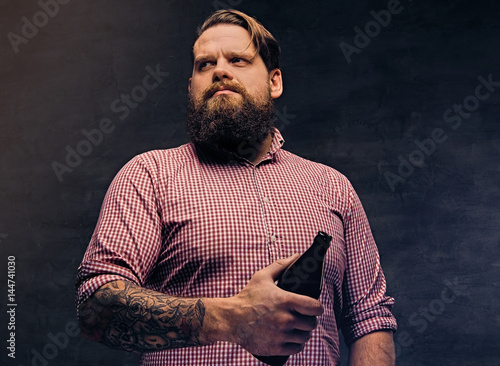 A bearded fat male holds a beer bottle.