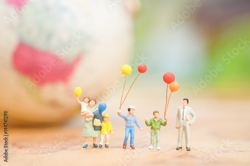 Miniature people, family and children with colorful ballons  standing in front of house. International Day of Families