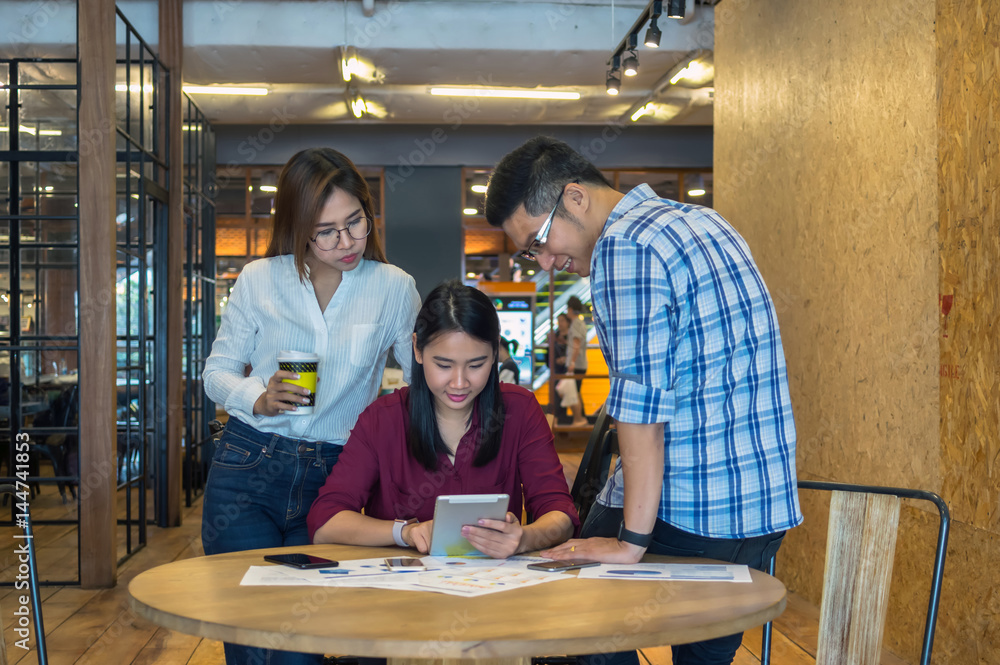 Group Of Asian Business people with casual suit Meeting in looking at the tablet action In the modern coffee shop, business group concept Group Of Asian Business people with casual suit Meeting in looking at the tablet action In the modern coffee shop, business group concept