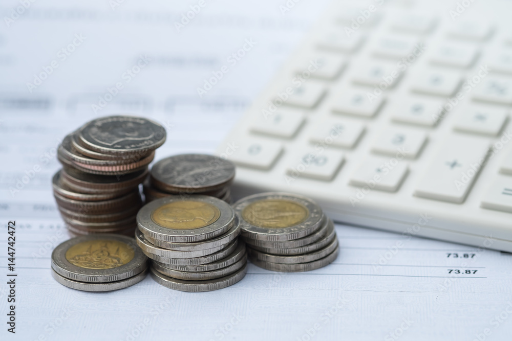 Stack of coins with calculator as background. Income, expenses, tax, financial data.