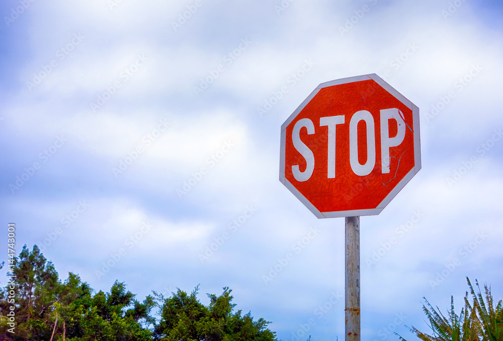 Stop road sign against cloudy sky.
