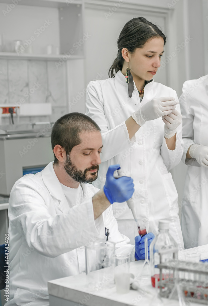 Group of scientists working with liquid test tube samples Group of scientists working with liquid test tube samples
