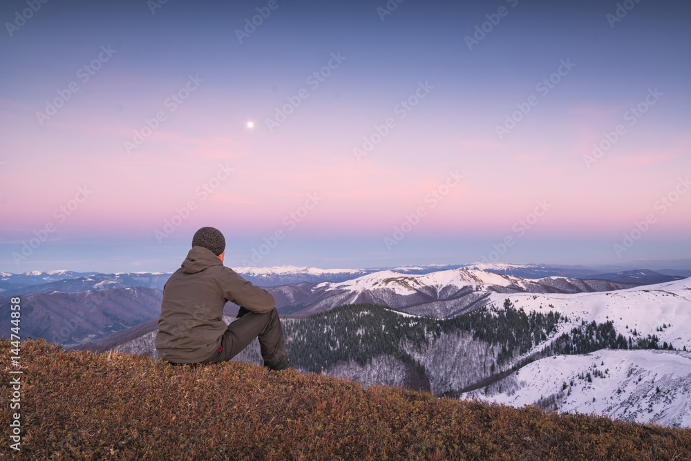 Man sitting on a hill and contemplate moon rising