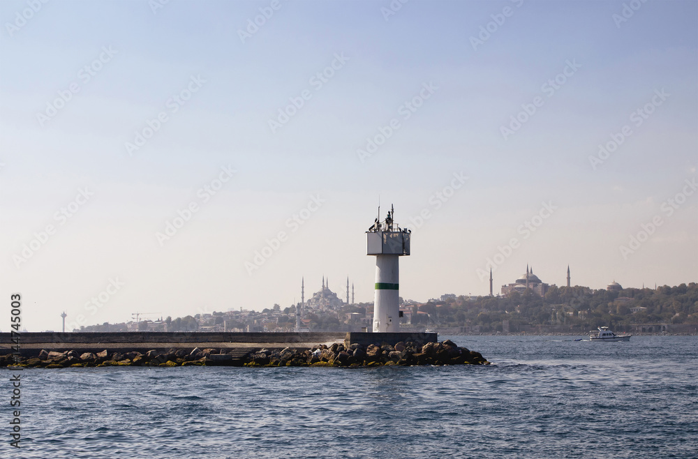 View of water breaker at Marmara sea near Kadikoy ferry station in Istanbul. Hagia Sophia, Blue Mosque and small boat are in the background.