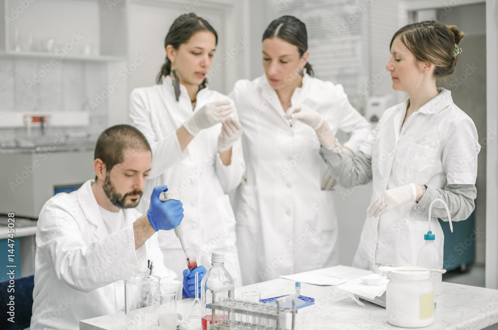 Group of scientists working with liquid test tube samples Group of scientists working with liquid test tube samples