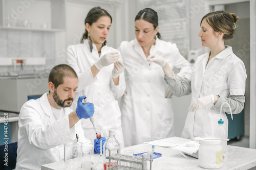 Group of scientists working with liquid test tube samples