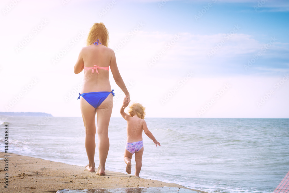 Mother with little baby walking along the beach
