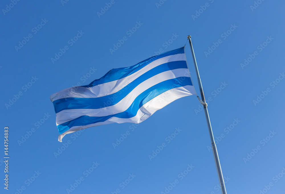 Waving Flag of Tallinn, Estonia, Blue and White stripes isolated on blue sky background