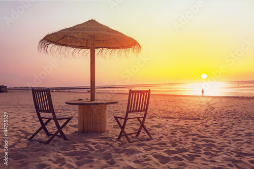 Wooden table and chairs with umbrella on the beach 