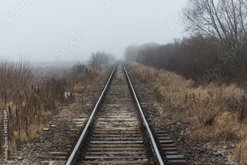 Empty railroad track going into a fog, outdoor landscape