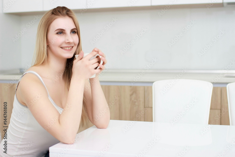 young woman With black hairdrinking coffee in the kitchen young woman With black hairdrinking coffee in the kitchen