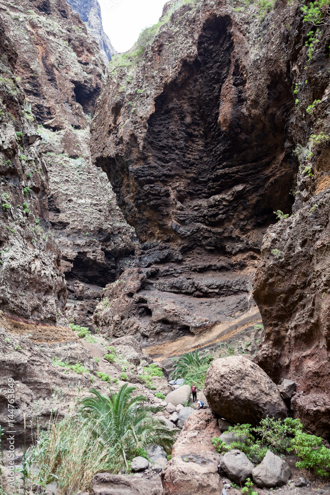 Huge brown rocks of the Masca Gorge. Hiking trail passing through the giant cliffs. Tenerife, Canaries, Spain