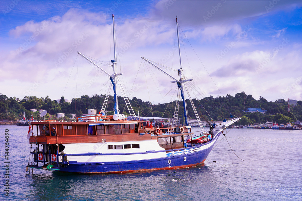 Indonesian wooden sailboat called pinisi, a  liveaboard ship for divers, or dive boat, near the island with the harbor.