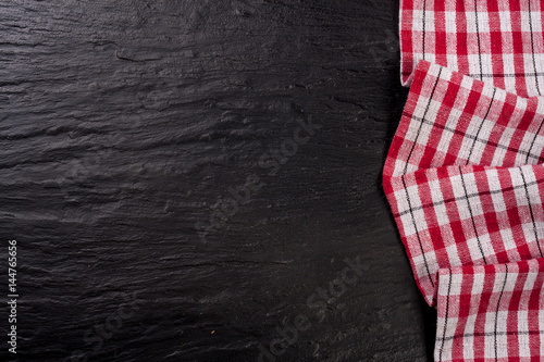Red checkered tablecloth on a dark stone background with copy space for your text. Top view
